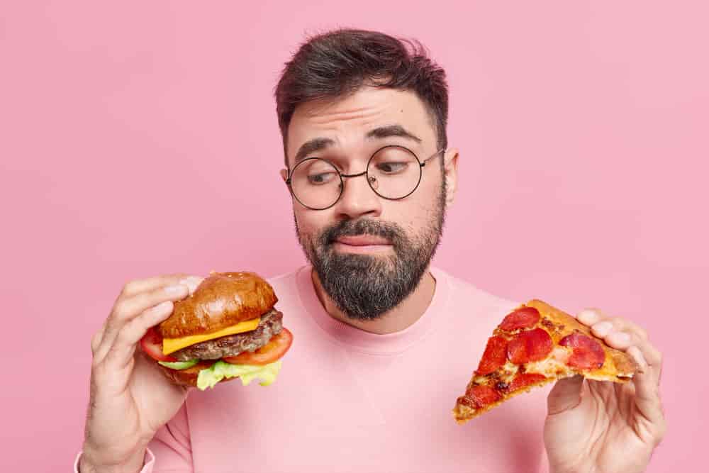 man-feels-hesitant-whether-eat-hamburger-pizza-prefers-eating-junk-food-wears-round-spectacles-jumper-min.jpeg